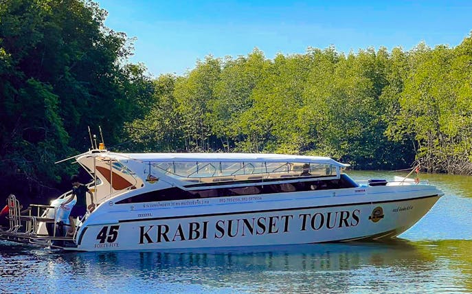 Speedboat for Krabi Sunset Tours on water near lush greenery, Phi Phi Islands.