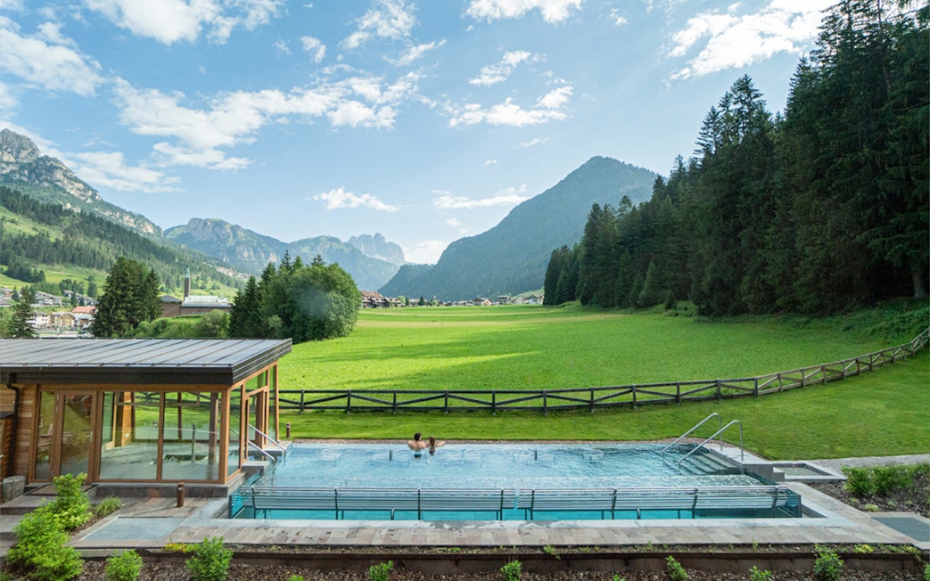 Couple relaxing in the pool at QC Terme Resort & Spa, Dolomiti, with mountain views.