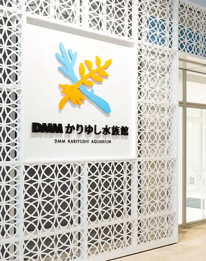 DMM Kariyushi Aquarium entrance sign with decorative wall pattern.
