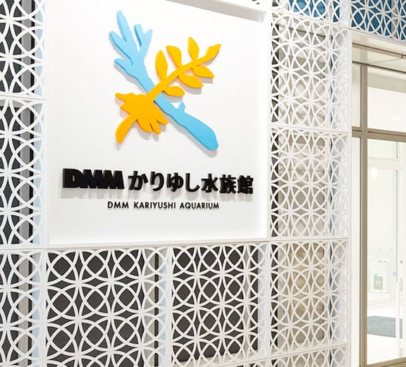 DMM Kariyushi Aquarium entrance sign with decorative wall pattern.