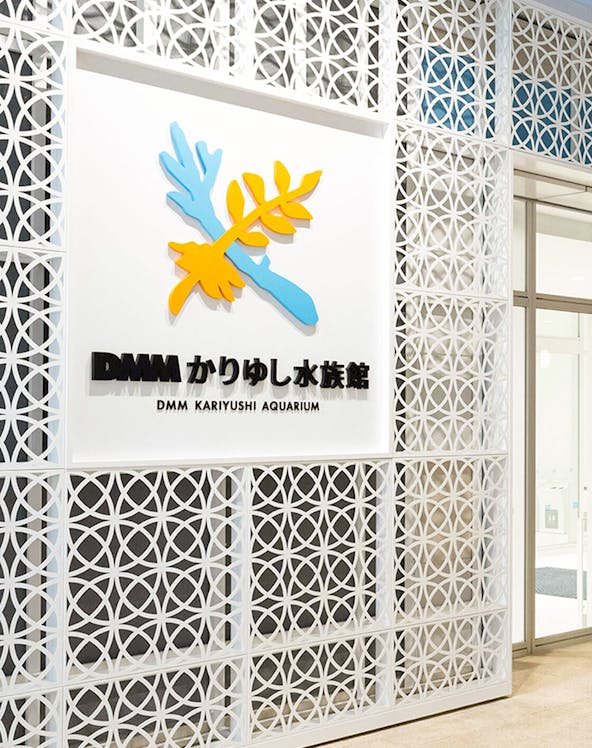 DMM Kariyushi Aquarium entrance sign with decorative wall pattern.