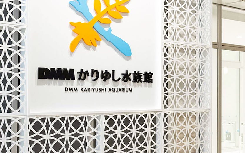 DMM Kariyushi Aquarium entrance sign with decorative wall pattern.