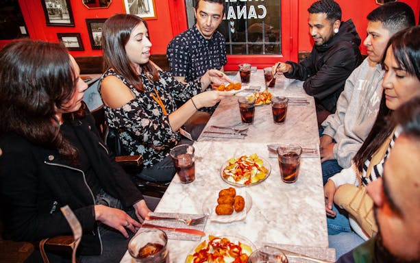 Group enjoying tapas at a table during a 3-hour guided food tour in La Barceloneta.