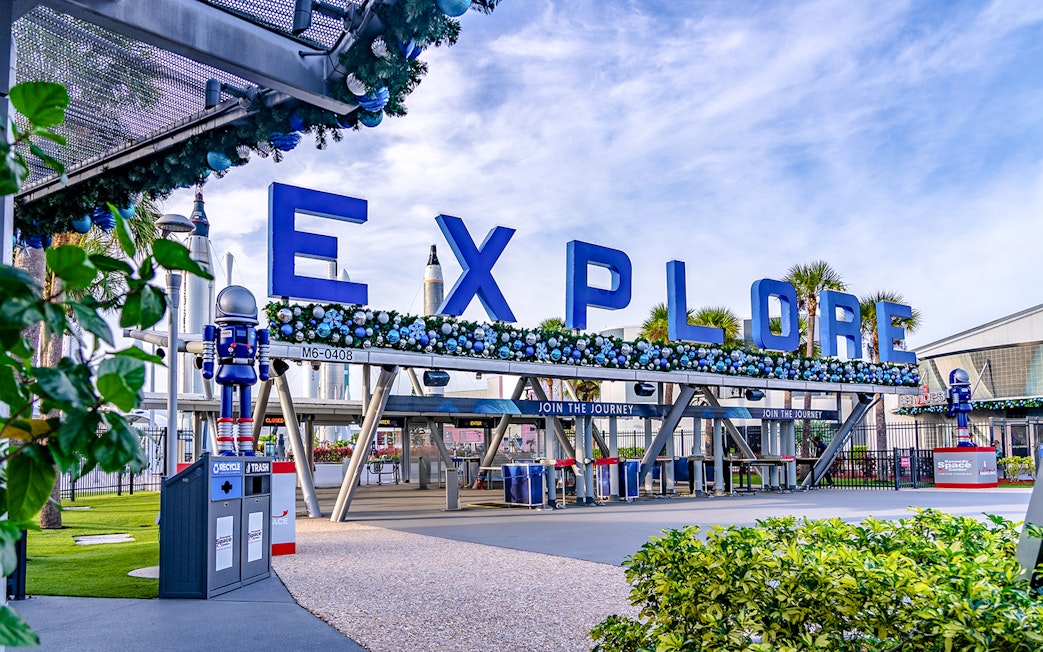 Entrance to Kennedy Space Center with "Explore" sign and astronaut figures.
