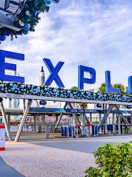 Entrance to Kennedy Space Center with "Explore" sign and astronaut figures.