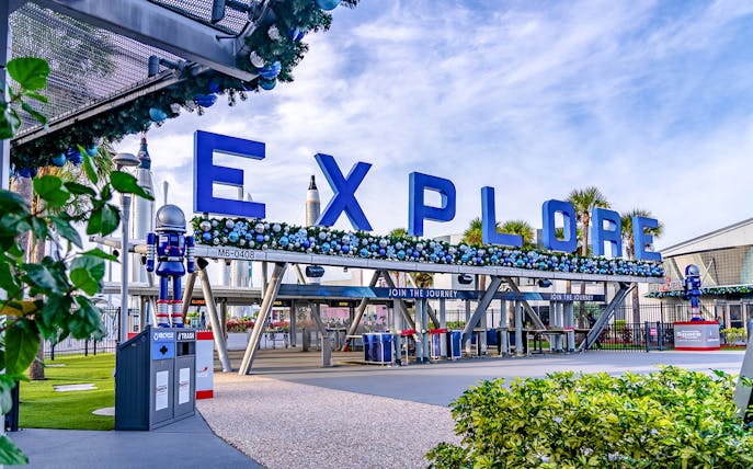 Entrance to Kennedy Space Center with "Explore" sign and astronaut figures.