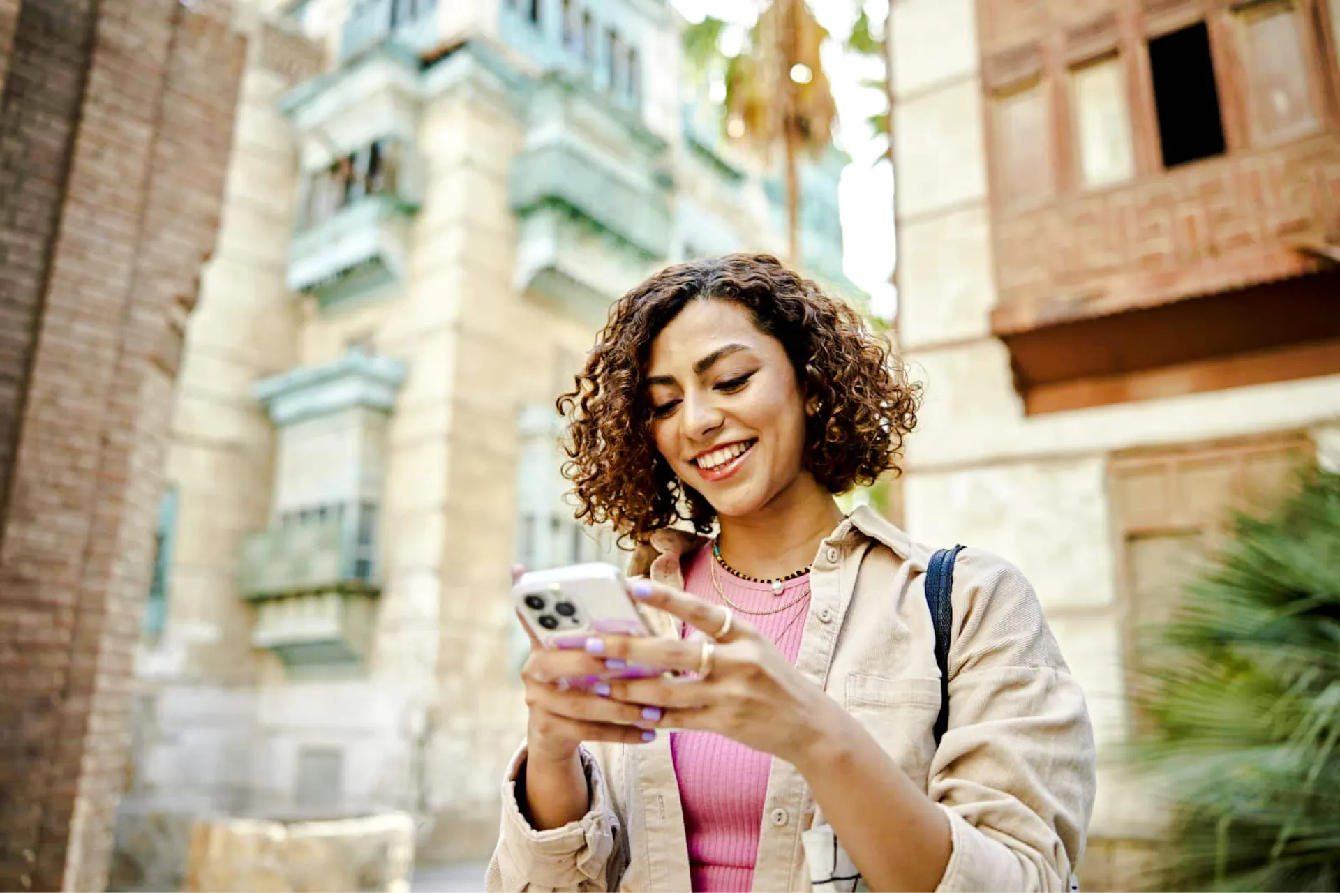 Person using smartphone in Lisbon with historic buildings in the background.