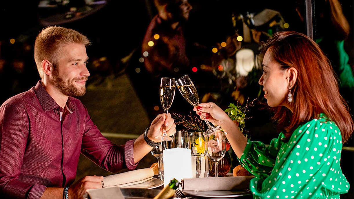 Couple toasting with champagne on Seine dinner cruise at 8:30pm.