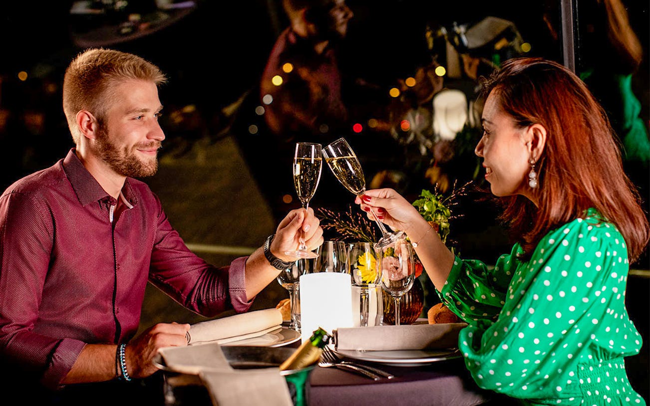 Couple toasting with champagne on Seine dinner cruise at 8:30pm.