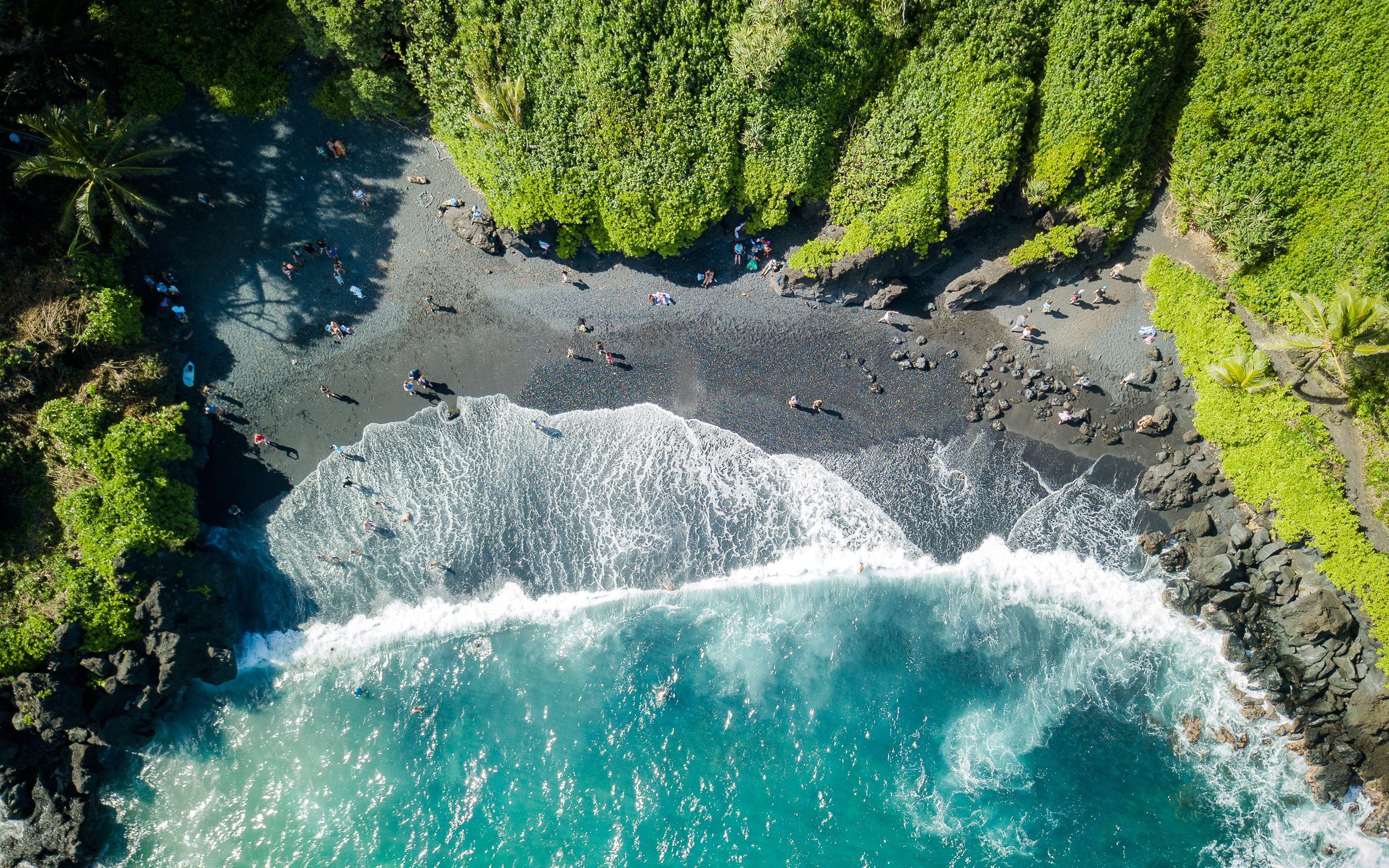 Aerial view of black sand beach and ocean waves at Waiʻanapanapa State Park, Hawaii.
