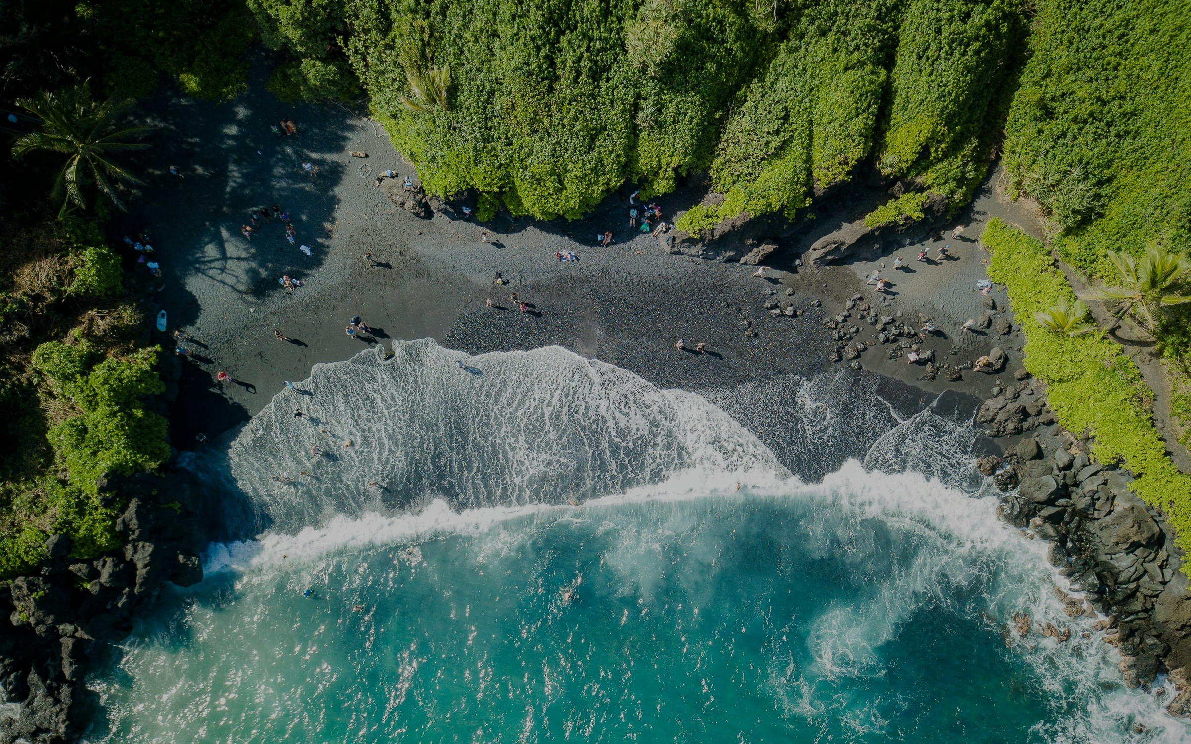 Aerial view of black sand beach and ocean waves at Waiʻanapanapa State Park, Hawaii.