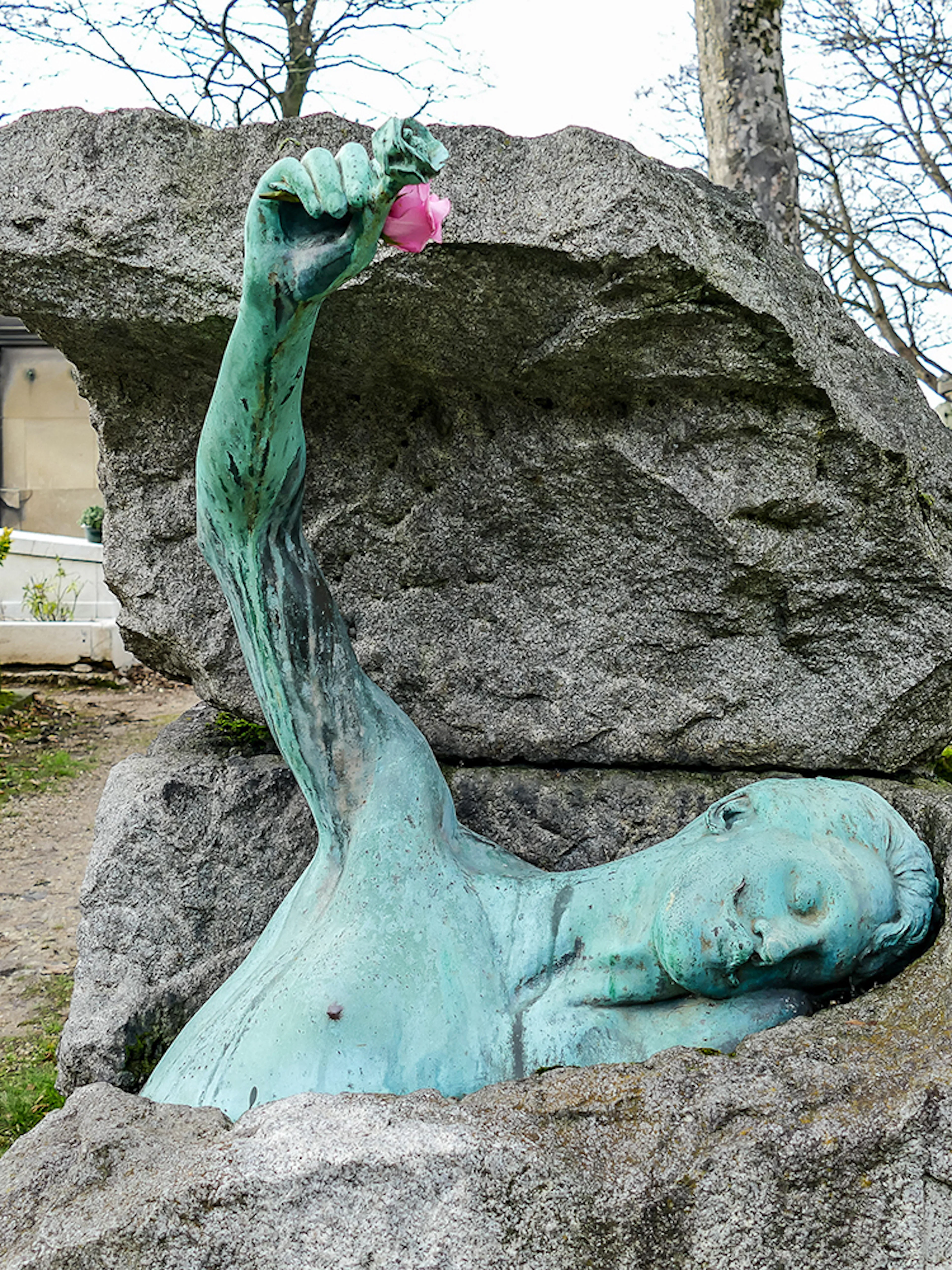 Sculpture of a figure emerging from a tomb at Père Lachaise Cemetery, Paris.