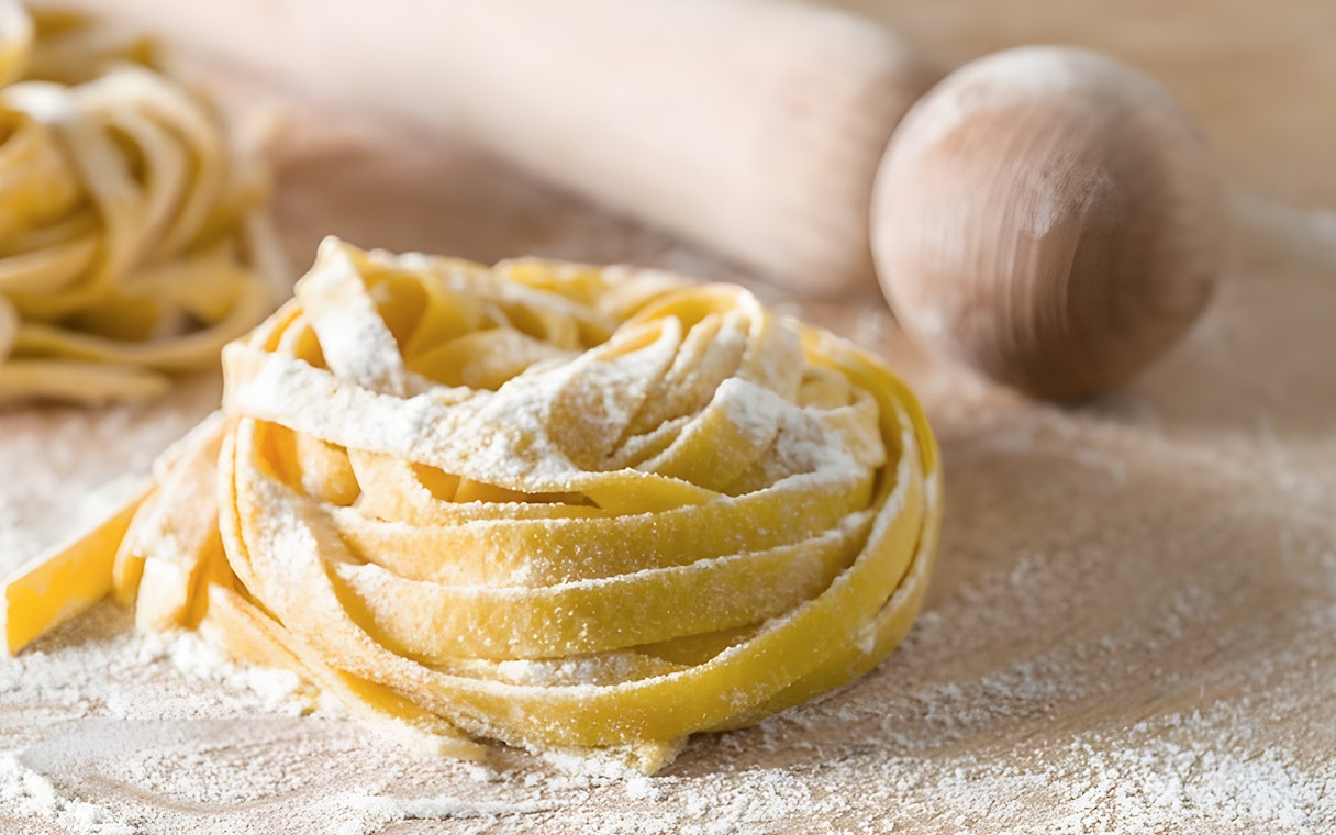 Fettuccine dough with flour and rolling pin in Rome cooking class.