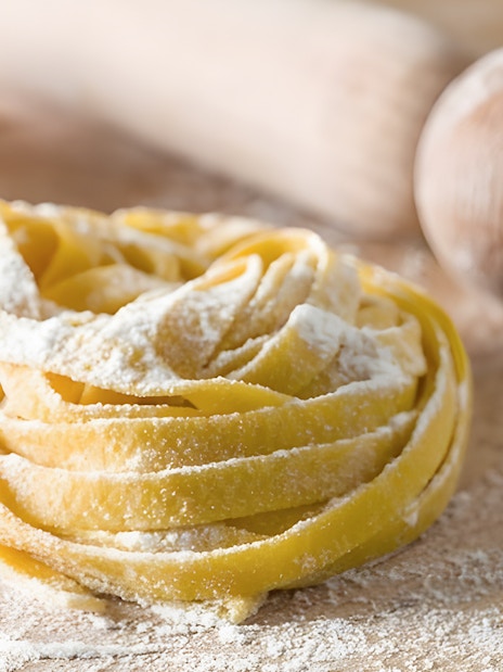 Fettuccine dough with flour and rolling pin in Rome cooking class.