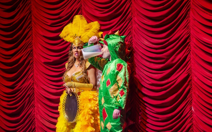 Performer in dragon costume drinking on stage at Piff the Magic Dragon show, Vegas.