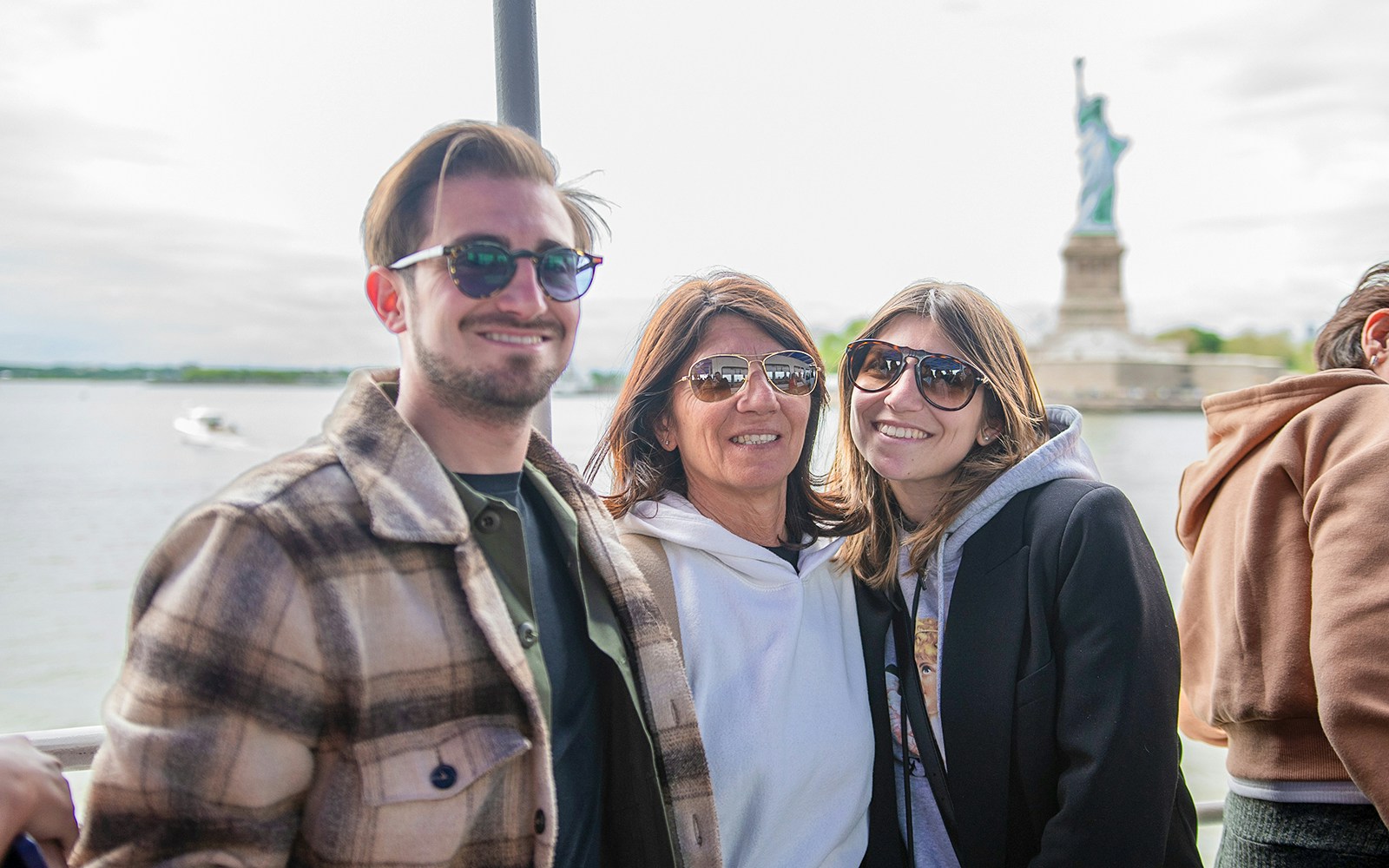 Tourist photographing Statue of Liberty from New York City sightseeing cruise.