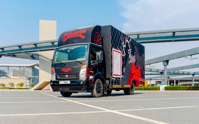 Smash room bus parked in an urban area with modern architecture in the background.