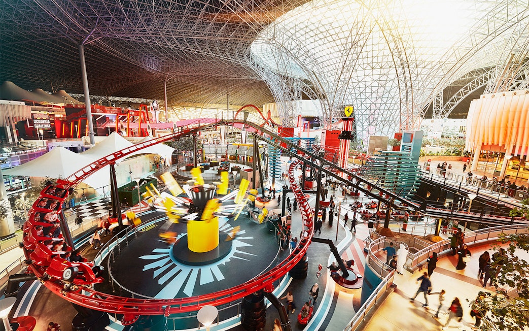 Ferrari World Abu Dhabi indoor roller coaster with vibrant red tracks and visitors exploring.