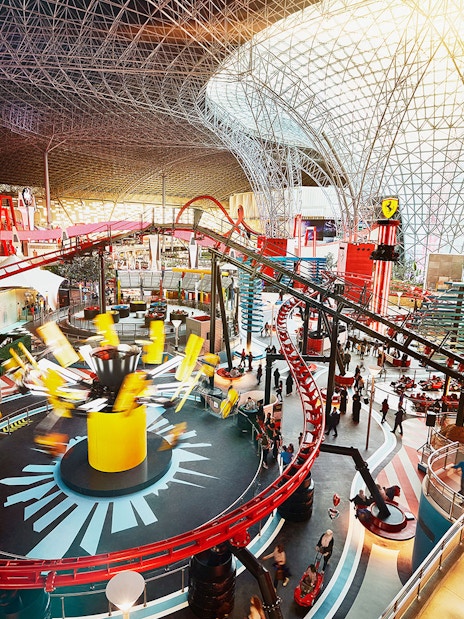 Ferrari World Abu Dhabi indoor roller coaster with vibrant red tracks and visitors exploring.