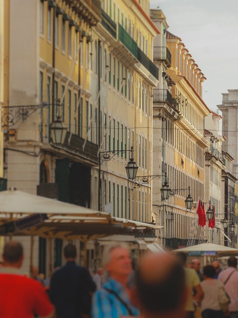 Rua Augusta Arch in Lisbon with bustling street and statue in view.