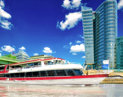 MS Wien ship on Danube Canal, Vienna, with UNIQA Tower in background.