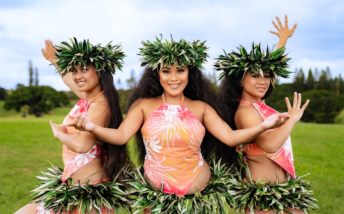 Dancers performing at Mauka Warriors Luau in traditional attire with greenery backdrop.