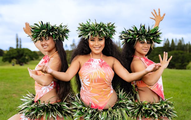Dancers performing at Mauka Warriors Luau in traditional attire with greenery backdrop.