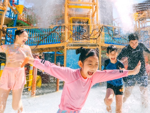 Children playing under a water splash at Vana Nava Water Jungle, Hua Hin.