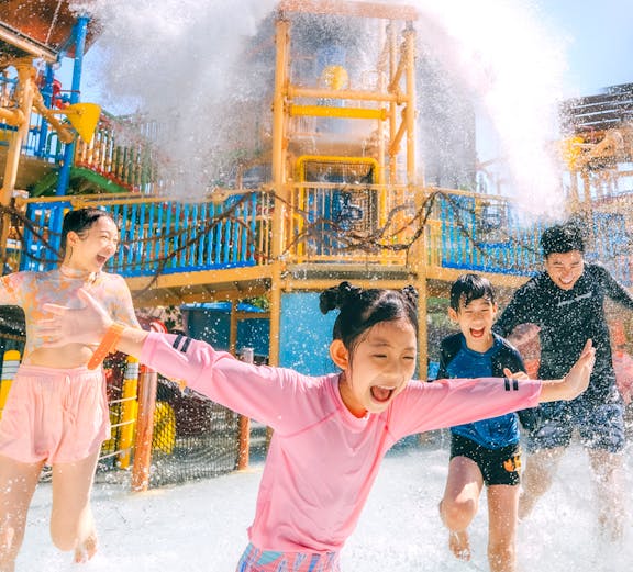 Children playing under a water splash at Vana Nava Water Jungle, Hua Hin.