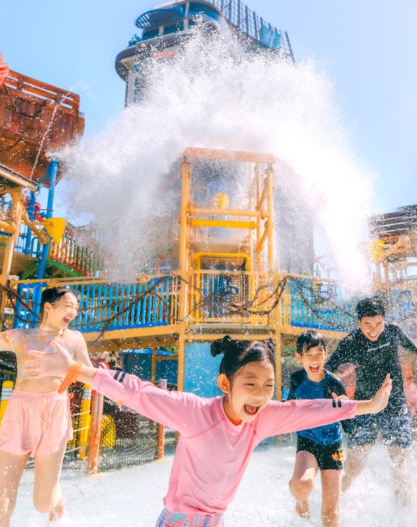 Children playing under a water splash at Vana Nava Water Jungle, Hua Hin.