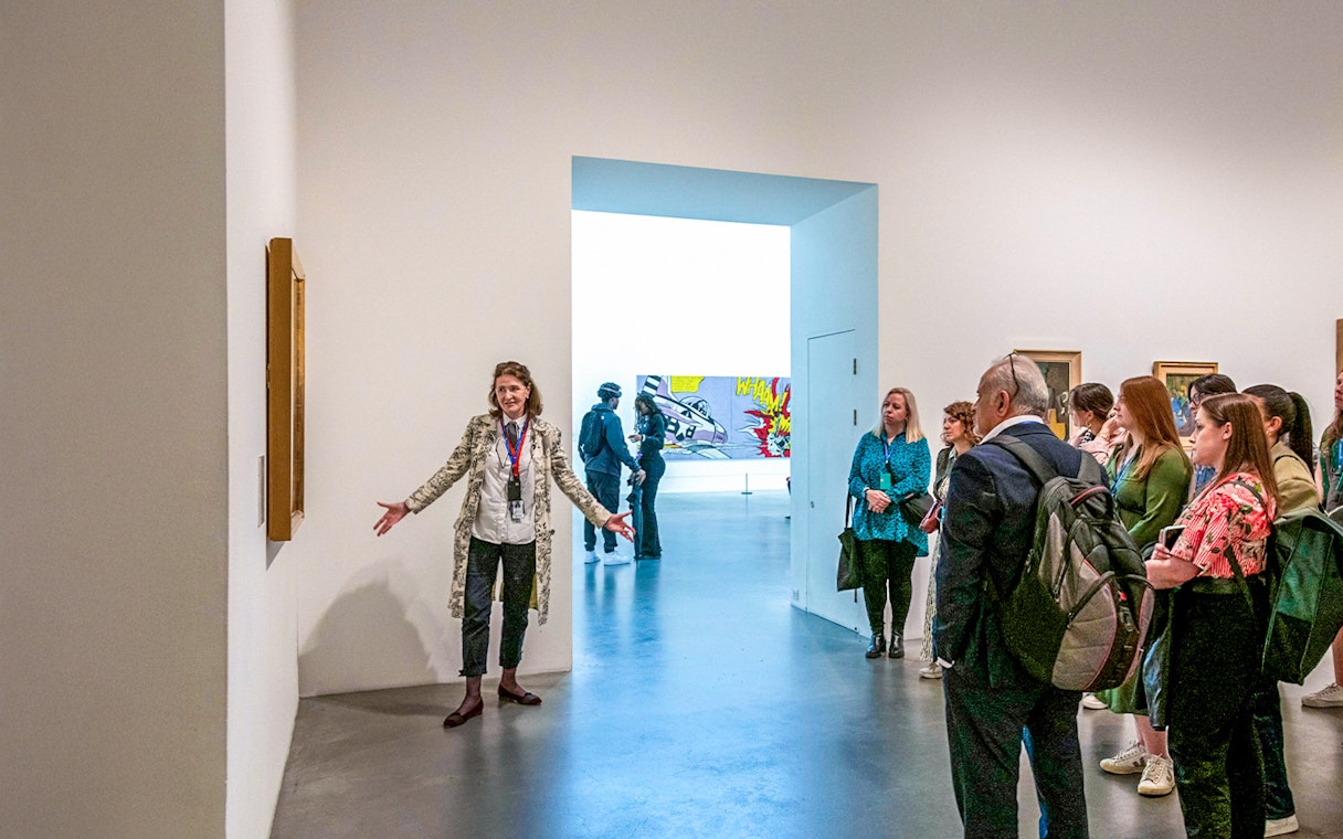 Guide explaining artwork to visitors inside Tate Modern.