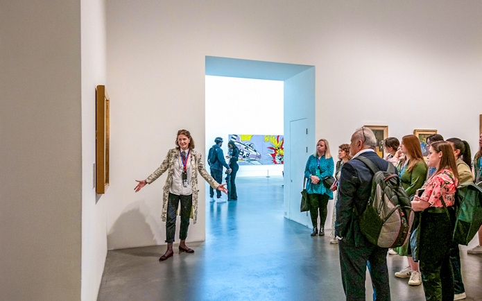 Guide explaining artwork to visitors inside Tate Modern.