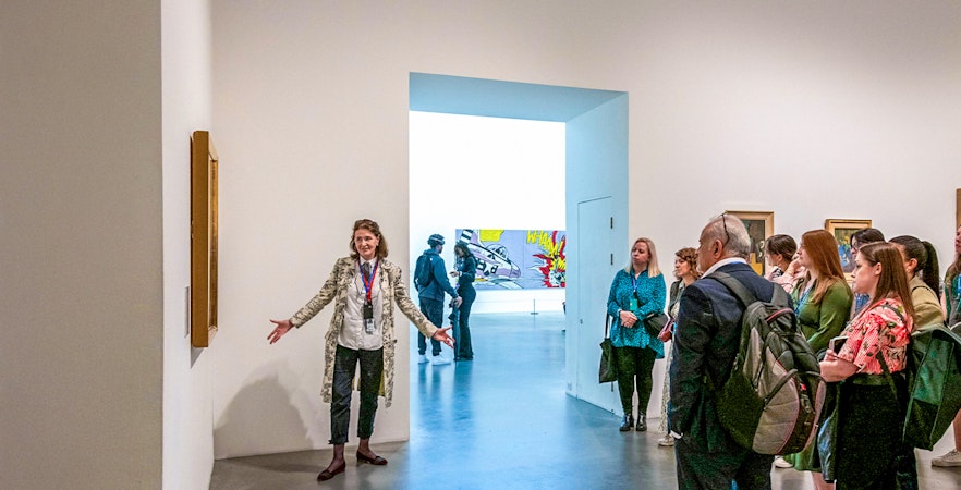 Guide explaining artwork to visitors inside Tate Modern.