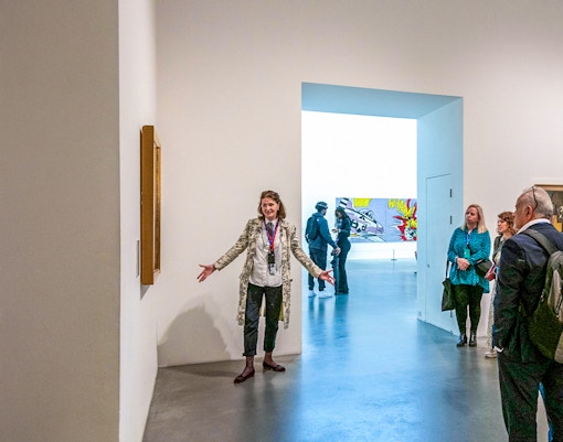 Guide explaining artwork to visitors inside Tate Modern.