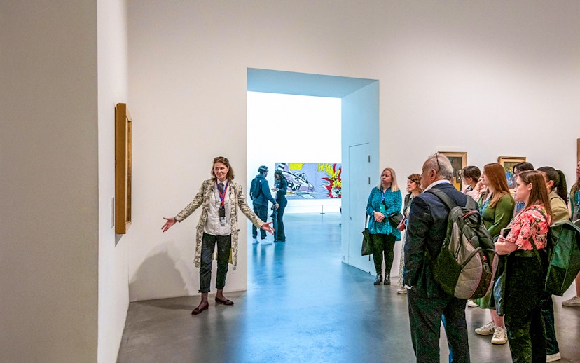 Guide explaining artwork to visitors inside Tate Modern.