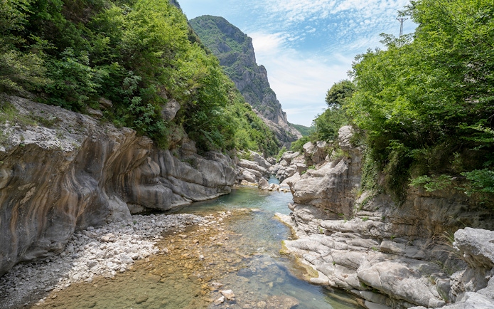 Scenic view of Bovilla Lake canyon with rocky cliffs and lush greenery during Gamti Mountain hiking tour.