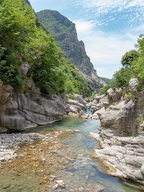 Scenic view of Bovilla Lake canyon with rocky cliffs and lush greenery during Gamti Mountain hiking tour.