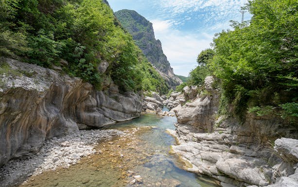 Scenic view of Bovilla Lake canyon with rocky cliffs and lush greenery during Gamti Mountain hiking tour.