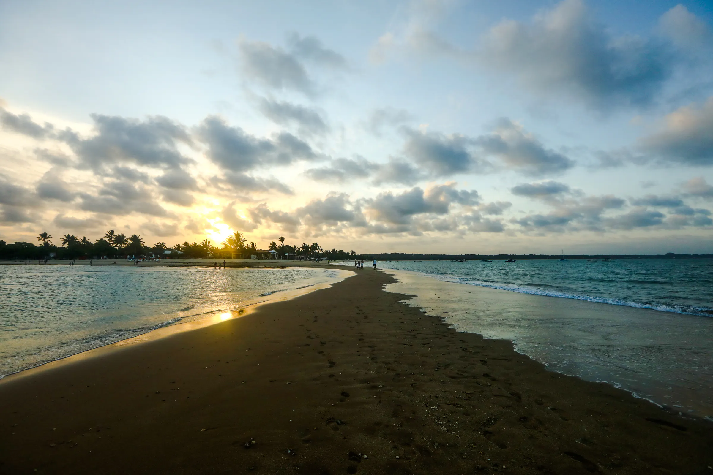 Sunset over Coroa Vermelha beach, Porto Seguro, with palm trees and ocean view.