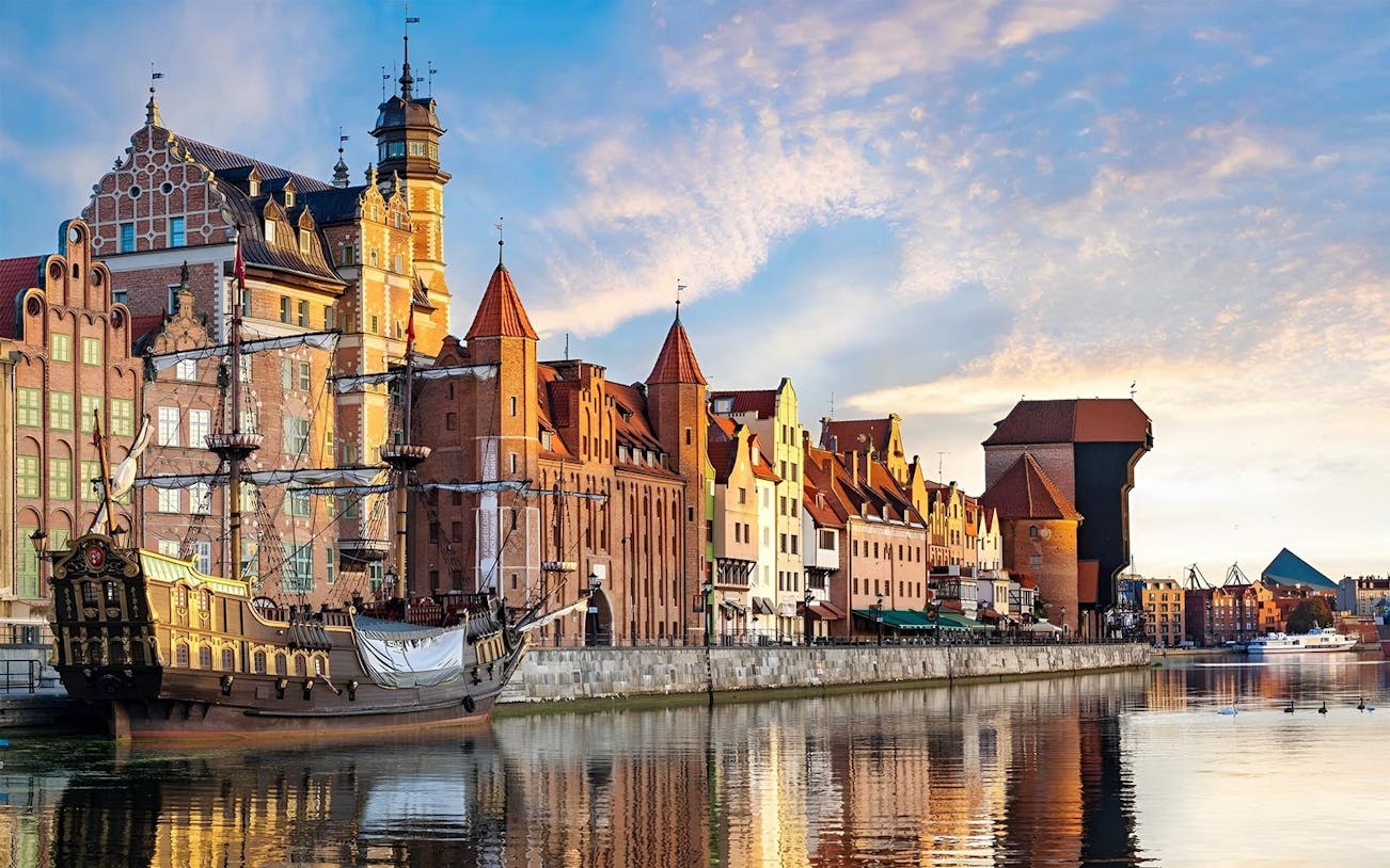 Historic Gdansk waterfront with medieval buildings and a replica pirate ship.