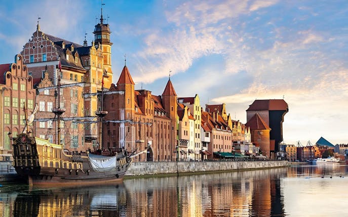 Historic Gdansk waterfront with medieval buildings and a replica pirate ship.
