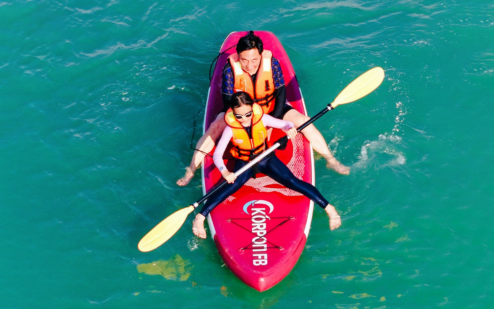 People kayaking on Langkawi Sunset Cruise with vibrant sky and calm waters in Malaysia.