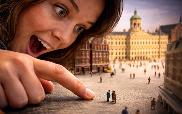 Person interacting with miniature figures at Miniature Museum, Amsterdam.