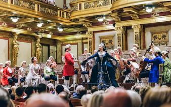Mozart Orchestra Concert with musicians in period costumes performing in an ornate concert hall.