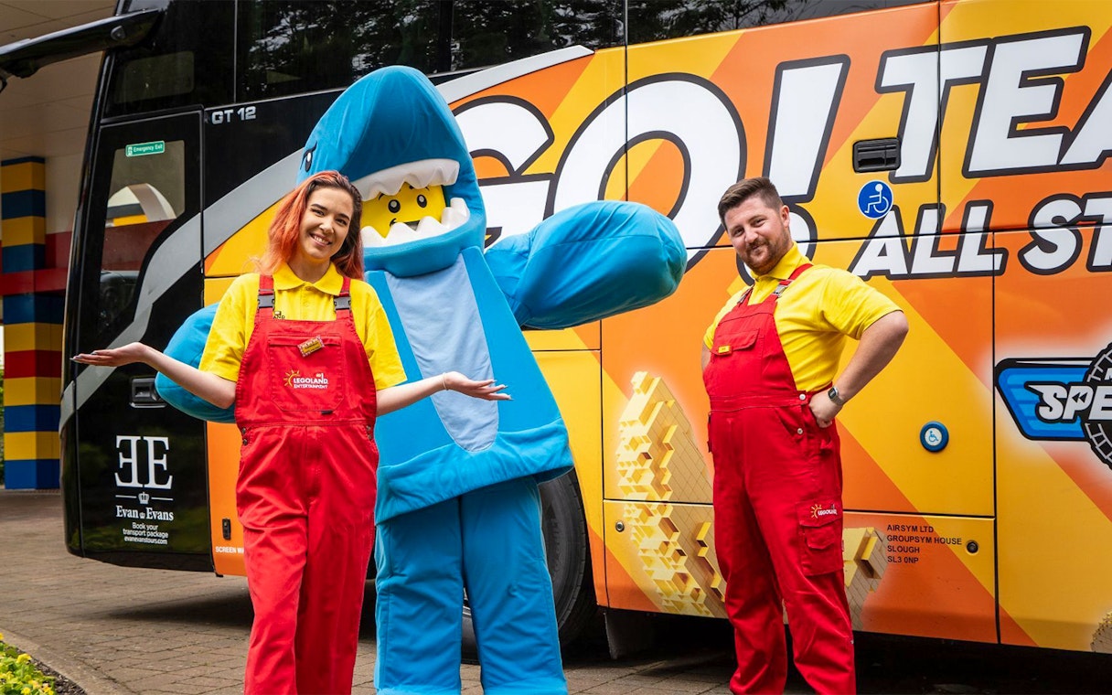 LEGOLAND® Windsor Resort staff and mascot in front of themed bus for London express tour.