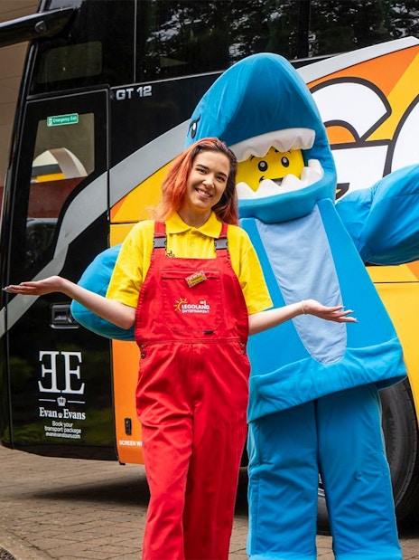 LEGOLAND® Windsor Resort staff and mascot in front of themed bus for London express tour.