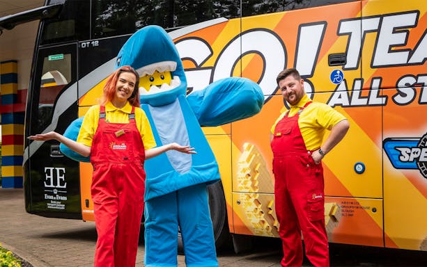 LEGOLAND® Windsor Resort staff and mascot in front of themed bus for London express tour.