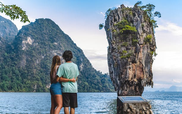 Couple admiring James Bond Island in Phang Nga Bay, Thailand.