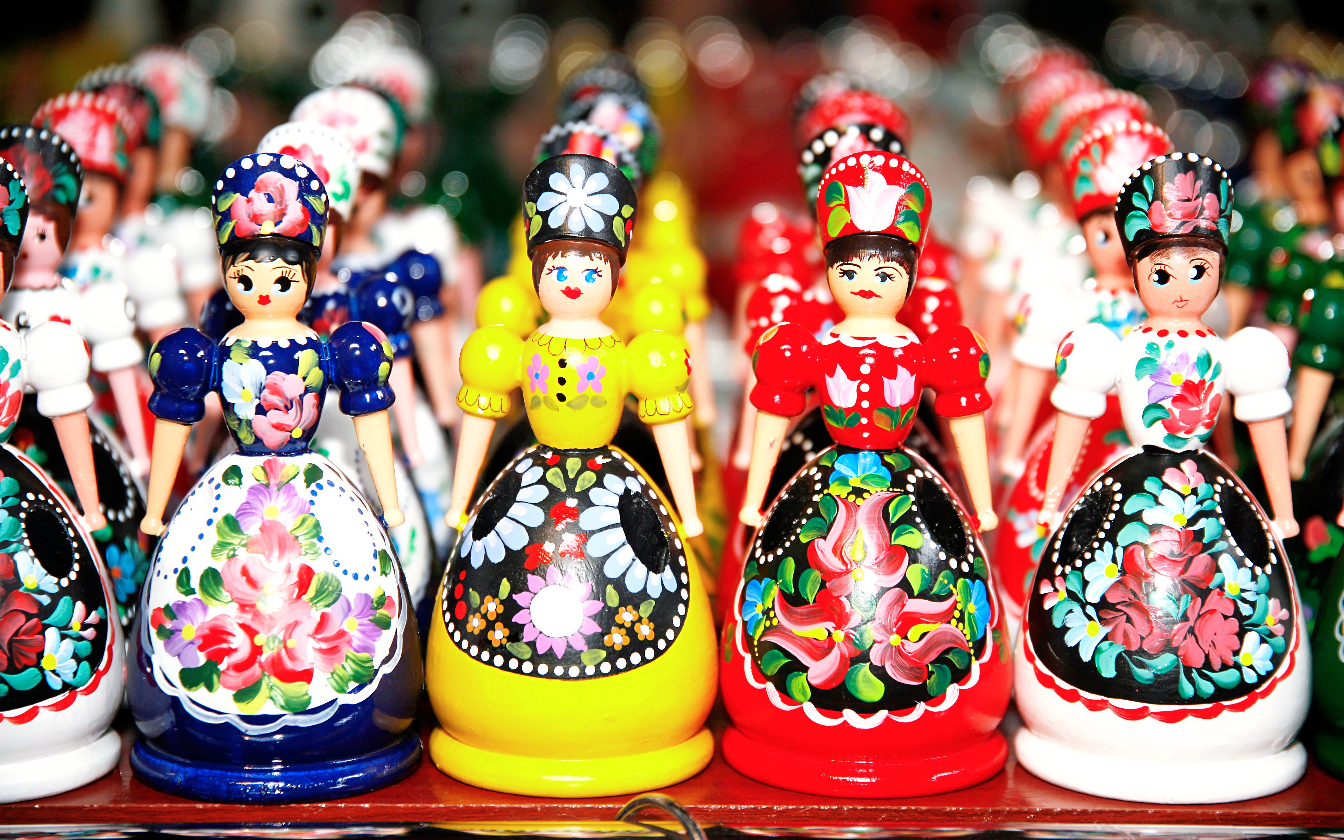 Wooden dolls in Hungarian folk costumes displayed in a row as souvenirs.