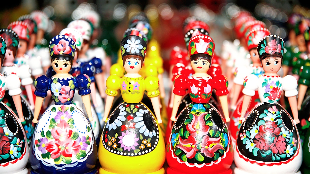 Wooden dolls in Hungarian folk costumes displayed in a row as souvenirs.